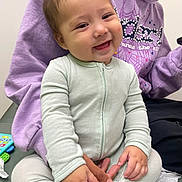 Aiden joined the competition — help win amazing prizes! baby, casual_clothing, child, closeup, cute, face, finger, hand, happy, holding, indoor, infant, lap, onesie, person, purple_hoodie, sitting, smile, toy, warm