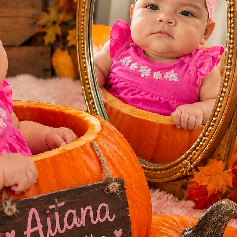 Aitana is registered to the contest to win money with this photo: baby, infant, child, portrait, pumpkin, autumn, fall, mirror, pink_bow, pink_dress, smiling, sitting, seasonal, indoor, photography, reflection, orange, leaves, cozy, five_months