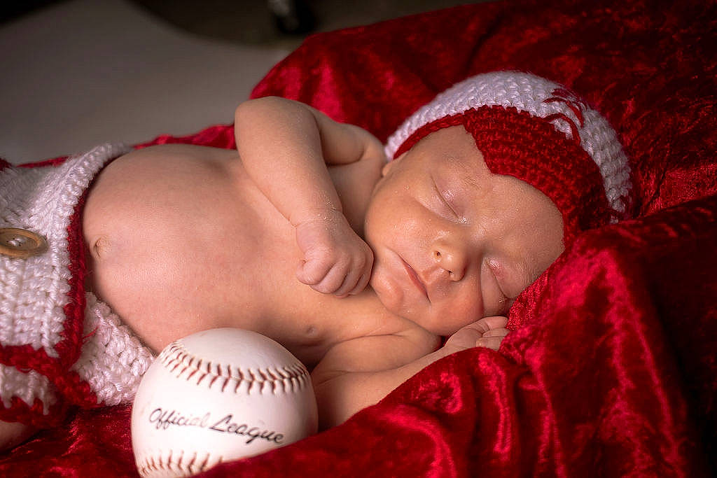 Mason is registered to the contest to win money with this photo: abdomen, baby, baby_products, baby_sleeping, ball, baseball_glove, bedtime, carmine, cheek, chest, child, comfort, flesh, headgear, headwear, linens, mouth, person, room, skin