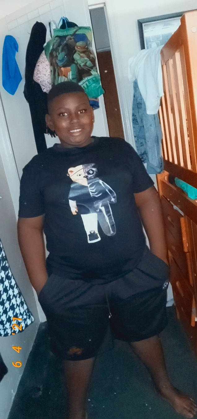 Malachi Coolkid is registered to the contest to win money with this photo: active_shirt, black_hair, blurred, costume, elbow, electric_blue, fun, knee, pattern, person, personal_protective_equipment, room, sleeve, smile, sportswear, street_fashion, t_shirt, thigh, top