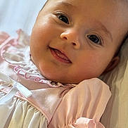 Sophia is registered to the contest to win money with this photo: baby, infant, smiling, face, eyes, pink_dress, white_dress, clothing, skin, cheeks, tongue, closeup, portrait, cute, happy, child, young, soft_light, indoor, person