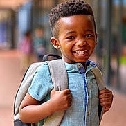 Islem a rejoint le concours — aidez-le/la à gagner de superbes lots ! african_american, backpack, blue_shirt, blurred_background, boy, casual_clothing, child, daylight, focus, happy, outdoor, person, portrait, positive_emotion, school, short_sleeves, smiling, standing, urban, young