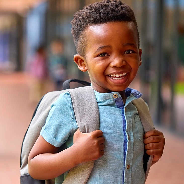 Islem a rejoint le concours — aidez-le/la à gagner de superbes lots ! african_american, backpack, blue_shirt, blurred_background, boy, casual_clothing, child, daylight, focus, happy, outdoor, person, portrait, positive_emotion, school, short_sleeves, smiling, standing, urban, young