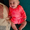 baby, bright, casual, child, coral_clothing, couch, cute, face, happy, indoors, infant, one_person, person, pillow, portrait, relaxed, sitting, skin, smiling, young
