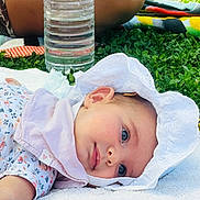 Victoria participe au concours pour gagner de l'argent avec cette photo : baby, bonnet, bottle, cap, clothing, face, grass, hat, head, herbal, herbs, lawn, person, photography, plant, portrait, quilt, summer, sunhat, waterbottle