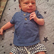 Damien is registered to the contest to win money with this photo: baby, child, infant, lying_down, portrait, blue_outfit, plaid_shorts, quilt, blanket, stars, indoors, bed, baby_fashion, short_hair, hands, feet, facial_expression, photography, home, cute