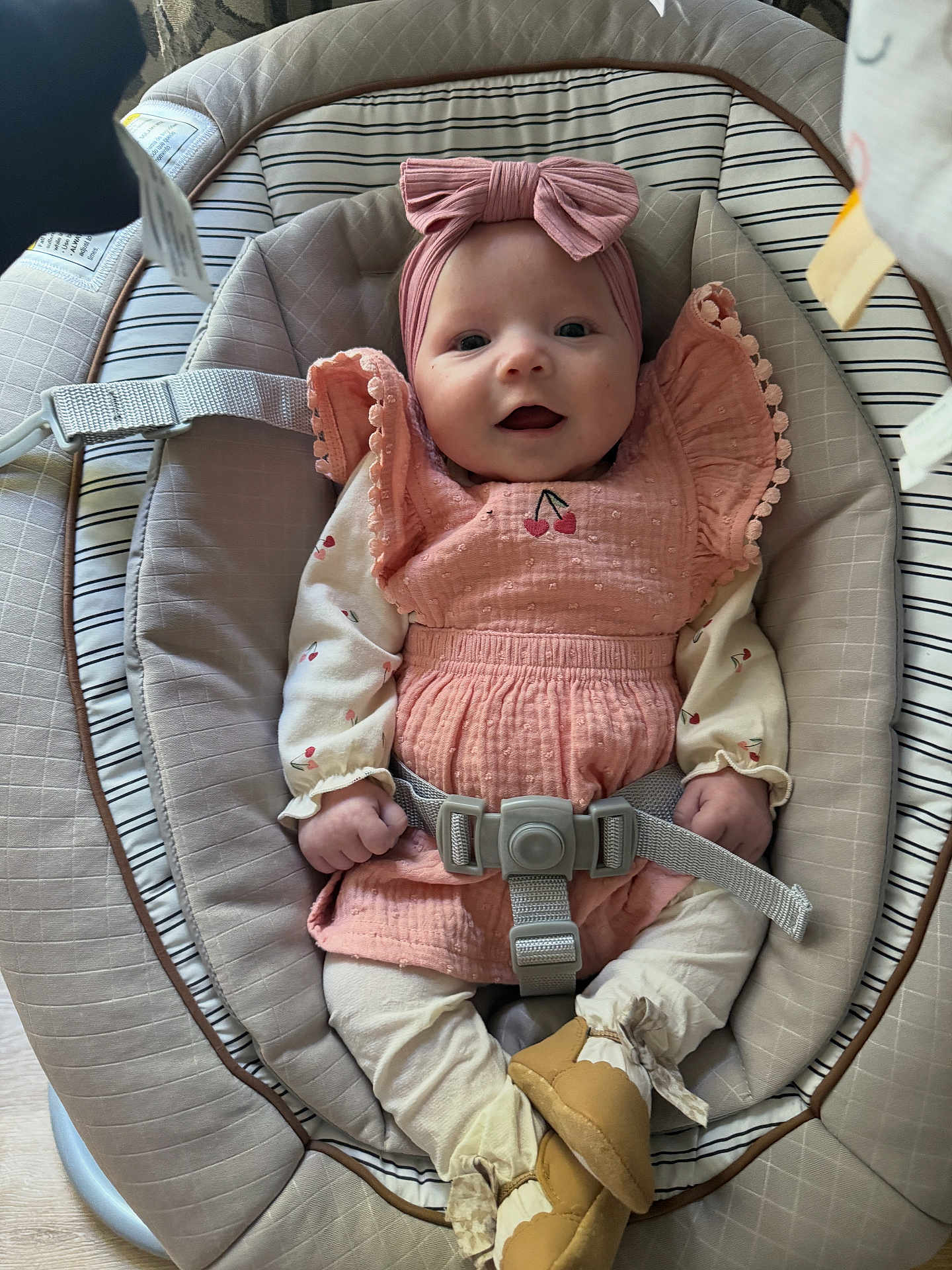 Paisleigh is registered to the contest to win money with this photo: baby, infant, smile, pink_dress, headband, baby_seat, straps, footwear, cute, happy, child, indoors, clothing, comfort, young, person, sitting, face, small_hands, soft_lighting