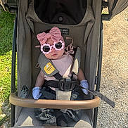 Paisleigh is registered to the contest to win money with this photo: baby, stroller, sunglasses, bow, pink, clothing, gloves, seatbelt, outdoor, grass, gravel, child, person, fashion, accessory, cute, summer, shade, baby_girl, portrait