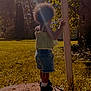 Kaylani is registered to the contest to win money with this photo: back_view, casual_clothing, child, curly_hair, daylight, grass, greenery, nature, outdoor, person, pole, shorts, sneakers, socks, standing, summer, sunbeam, sunlight, tree, yard