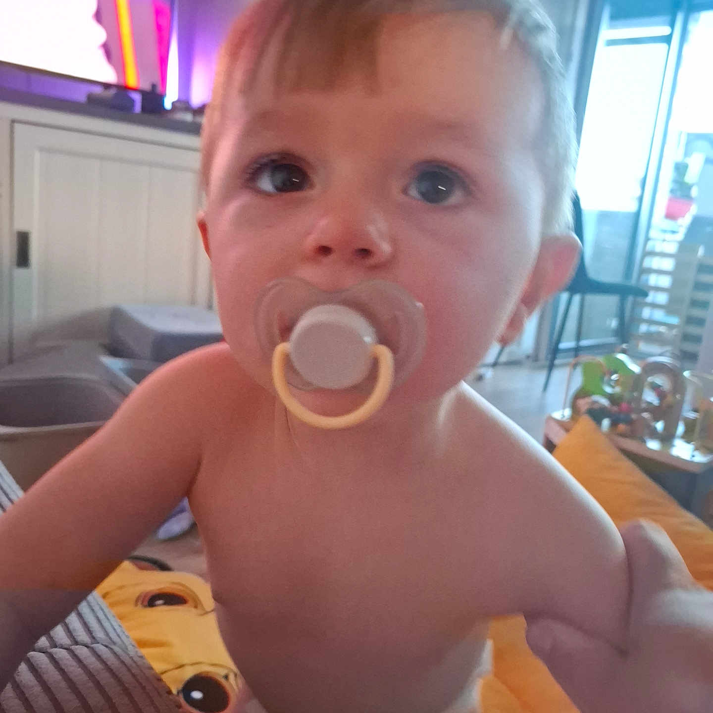 Noah participe au concours pour gagner de l'argent avec cette photo : child, closeup, couch, curious, cushion, daylight, diaper, expression, face, furniture, hair, hand, indoor, living_room, pacifier, person, skin, toddler, toy, window