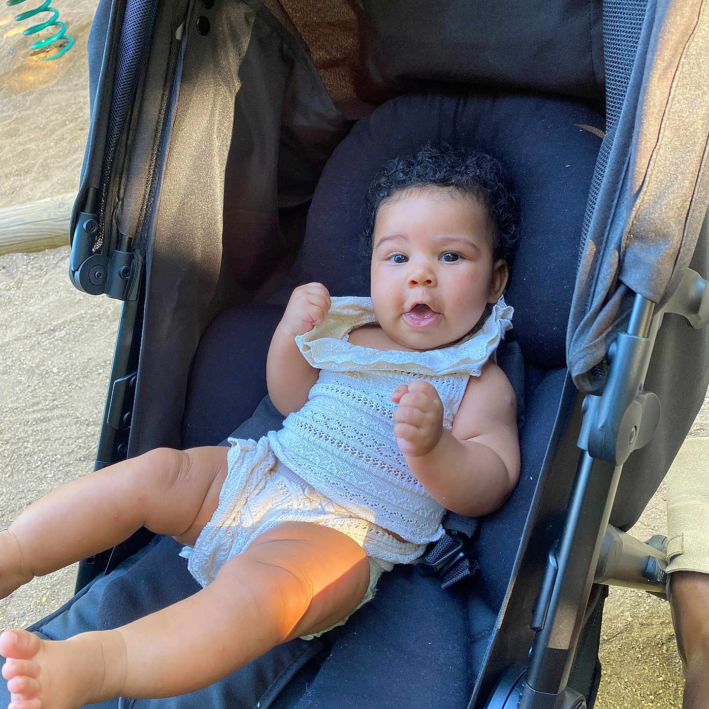 Lenaëlle participe au concours pour gagner de l'argent avec cette photo : baby, child, comfort, curly_hair, cute, expression, face, hands, infant, legs, outdoor, person, playful, relaxing, seat, stroller, summer, sunlight, white_outfit, young