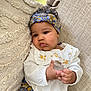 baby, beige, child, comfortable, couch, cozy, curly_hair, cute, embroidered_clothing, fingers, floral_pattern, hands, headband, indoor, portrait, sitting, soft_light, textured_fabric, white_top, young_child