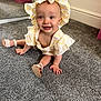 Arabella is registered to the contest to win money with this photo: baby, child, smiling, sitting, carpet, floor, hat, yellow, white, clothing, footwear, shoe, indoor, mirror, storage_box, room, furniture, cute, happy, portrait