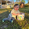 Judson is registered to the contest to win money with this photo: toddler, child, grass, bucket, outdoor, sunlight, blue_eyes, smiling, casual_clothing, socks, tree_stump, porch, house, spring, nature, playful, daylight, greenery, toy, person