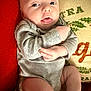 baby, infant, face, tongue, onesie, clothing, cushion, pillow, holiday, indoor, cute, skin, person, expression, red, grey, comfort, lying, closeup, child