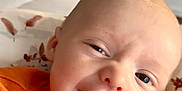 Monroe is registered to the contest to win money with this photo: baby, smiling, orange_sweater, indoor, closeup, face, child, happy, infant, bed, blanket, furniture, dresser, person, portrait, cute, skin, young, head, expression