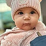 baby, child, face, hat, pink, pom_poms, jacket, fuzzy_clothing, portrait, close_up, cute, infant, warm_clothing, indoor, person, young_child, soft_texture, winter_clothing, large_eyes, adorable