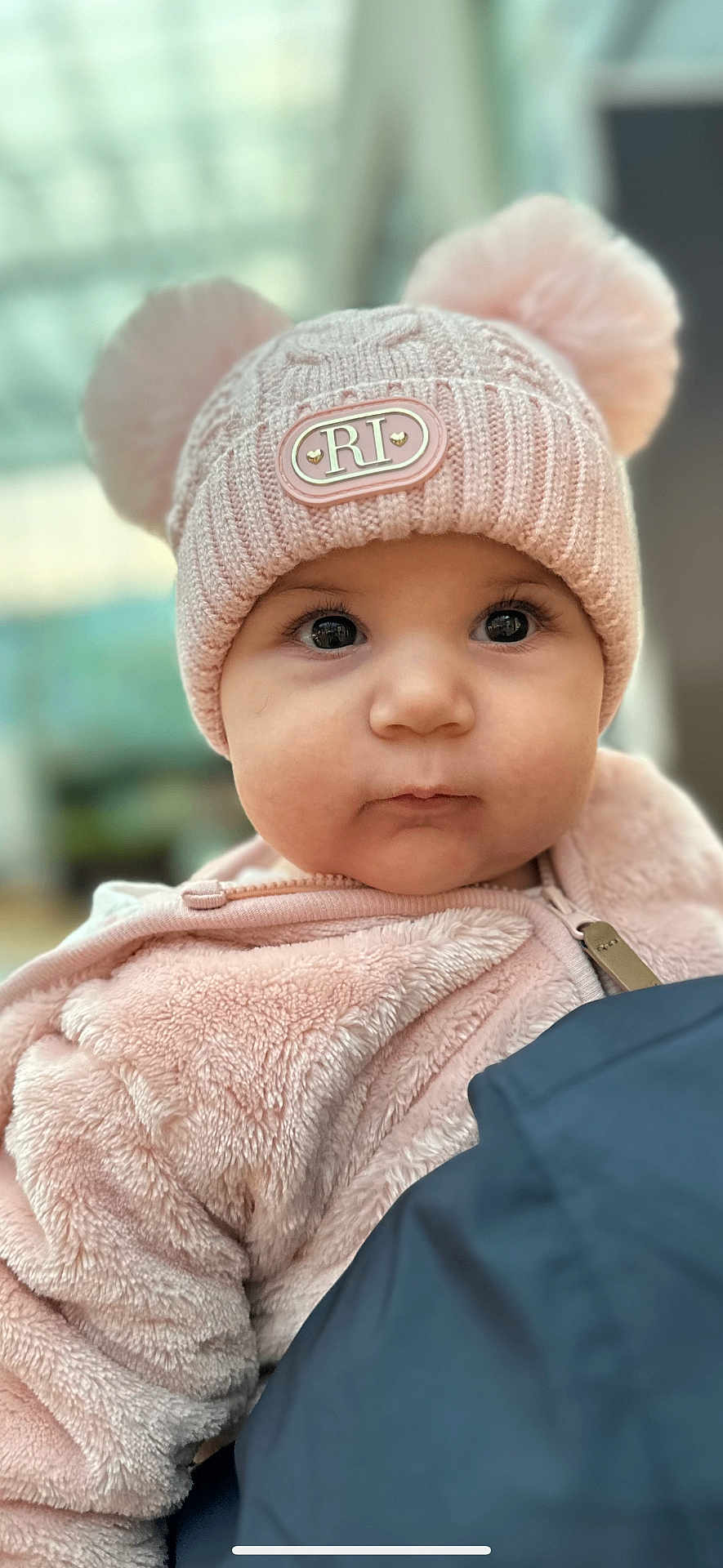 Celine is registered to the contest to win money with this photo: baby, child, face, hat, pink, pom_poms, jacket, fuzzy_clothing, portrait, close_up, cute, infant, warm_clothing, indoor, person, young_child, soft_texture, winter_clothing, large_eyes, adorable