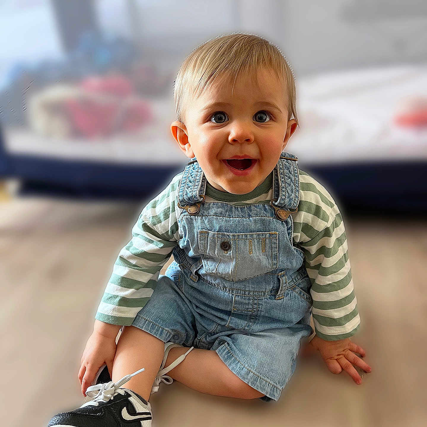 Isaac participe au concours pour gagner de l'argent avec cette photo : baby, blue_eyes, casual_clothing, child, cute, denim_overalls, fashion, floor, happy, home, indoor, person, portrait, short_hair, sitting, smiling, sneakers, striped_shirt, toddler, young_child