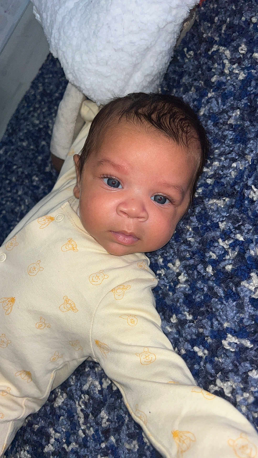 Cairo-Cruz joined the competition — help win amazing prizes! baby, infant, blue_eyes, onesie, carpet, textured, lying_down, cute, face, person, child, indoors, clothing, pattern, soft, young, skin, head, expression, curious