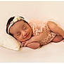 Sofia is registered to the contest to win money with this photo: newborn, baby, sleeping, headband, pink_outfit, lace, pillow, smile, peaceful, infant, cute, soft_texture, portrait, resting, hands_together, feet, closeup, studio, warm_tones, adorable