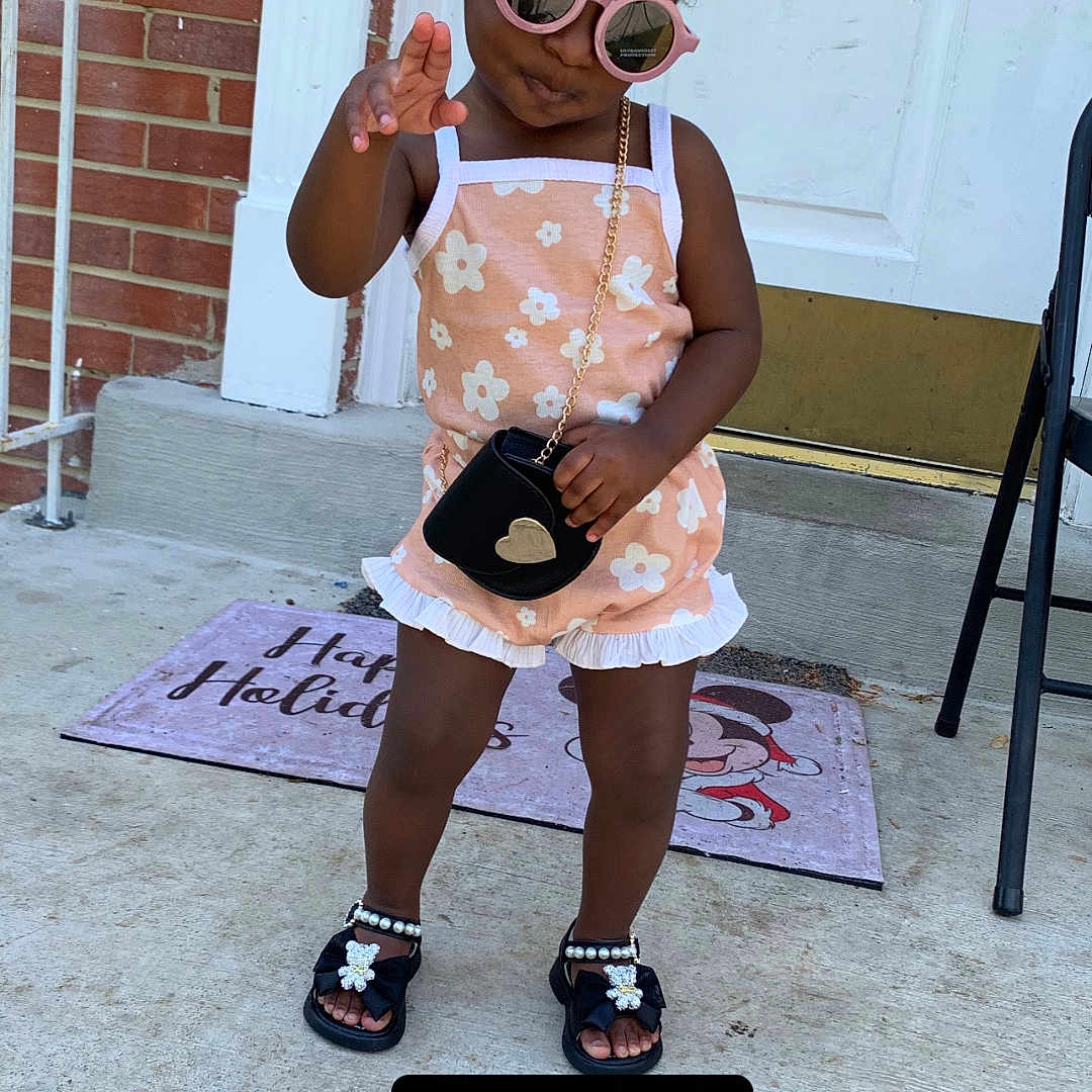 Zanaiya is registered to the contest to win money with this photo: toddler, child, sunglasses, colorful_beads, romper, sandals, purse, porch, brick_wall, door, mat, chair, concrete, outdoor, fashion, cute, posing, summer, accessories, happy