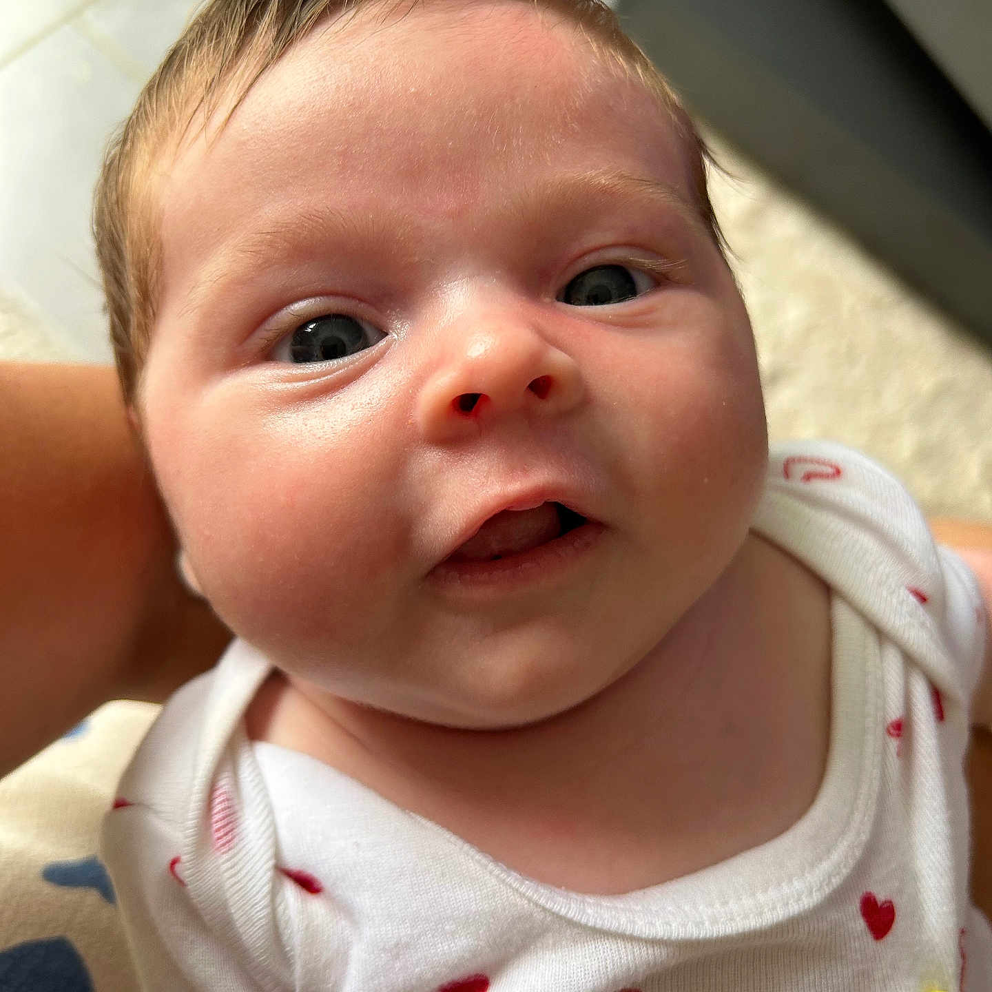 Julia a rejoint le concours — aidez-le/la à gagner de superbes lots ! baby, child, closeup, clothing, cute, expression, eyes, face, heart_pattern, holding, human, indoor, infant, mouth, newborn, onesie, person, portrait, skin, soft_light