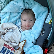 Naveen joined the competition — help win amazing prizes! baby, blanket, car_seat, bib, clothing, face, infant, person, smile, blue_blanket, soft_texture, indoor, cute, child, newborn, portrait, seatbelt, fabric, comfort, moms_mvp