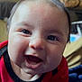Russel is registered to the contest to win money with this photo: baby, smiling, face, closeup, red_clothing, blanket, indoor, happy, child, person, portrait, skin, head, infant, eyes, mouth, cheeks, cozy, warm, soft