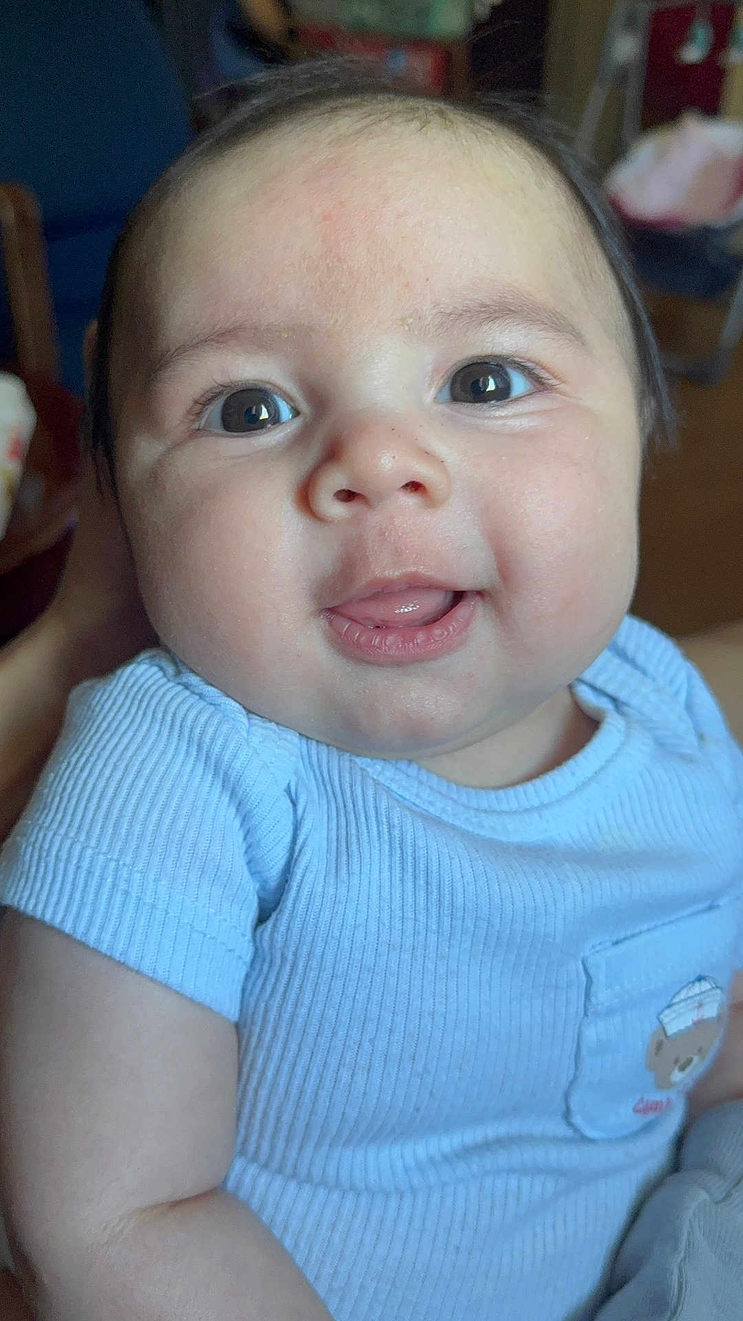 Russel is registered to the contest to win money with this photo: baby, child, face, smile, blue_shirt, indoor, portrait, cute, infant, skin, eyes, mouth, cheeks, person, clothing, young_child, closeup, happy, sitting, toddler