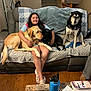 Demetri is registered to the contest to win money with this photo: girl, dog, couch, living_room, blanket, stairs, wood_floor, water_bottle, table, book, smiling, pet, indoor, cozy, casual, relaxing, furniture, home, person, animal