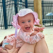 Oakley joined the competition — help win amazing prizes! baby, child, smiling, hat, pink, floral, outdoor, fence, person, legs, diaper, happy, cute, blue_eyes, sunhat, holding, skin, daylight, playful, joyful