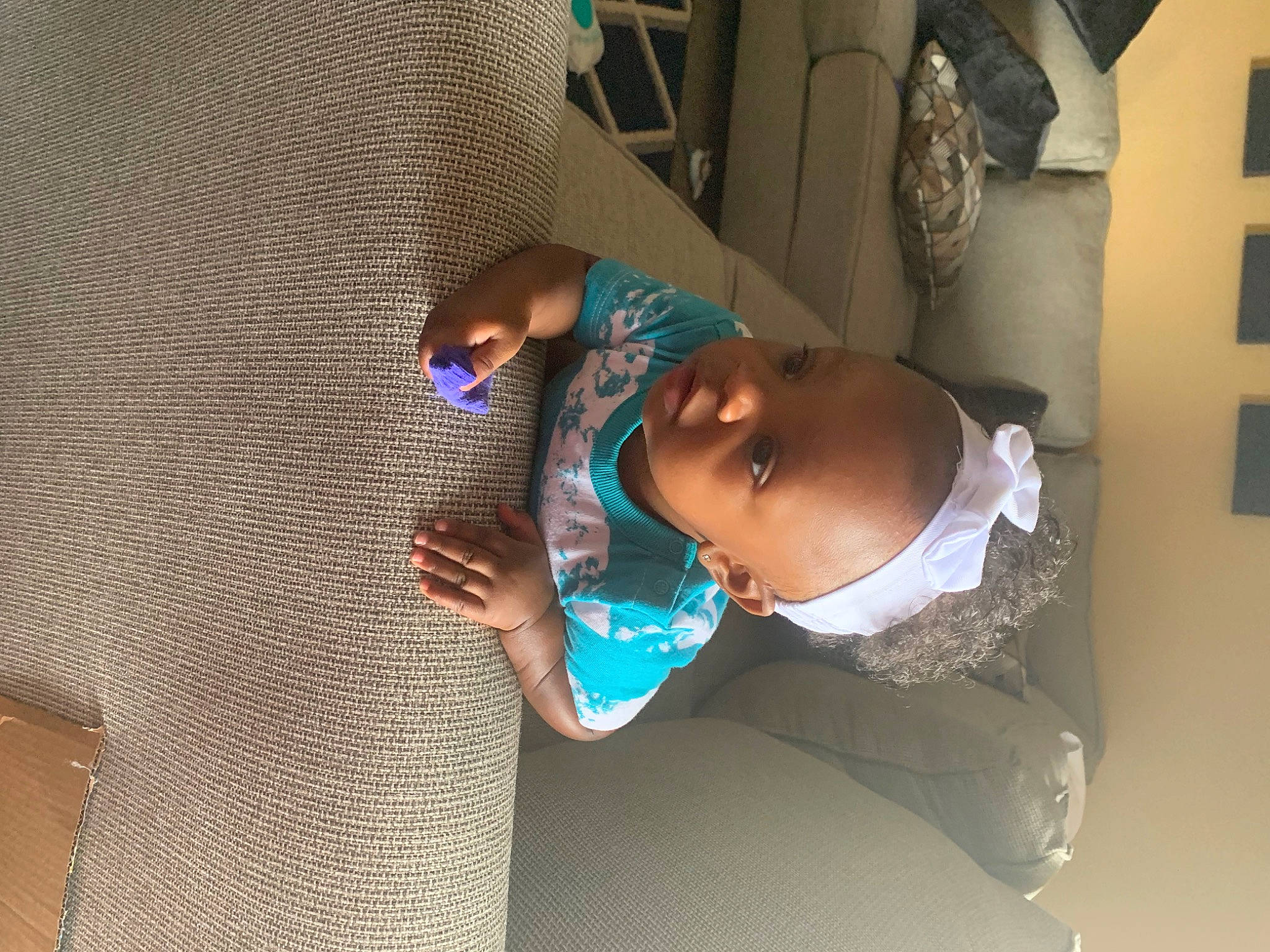 Khailani is registered to the contest to win money with this photo: baby, baby_products, baby_toddler_clothing, child, comfort, elbow, electric_blue, eyewear, fashion_accessory, flooring, fun, hat, leisure, pattern, person, room, sitting, sun_hat, sunglasses, toddler