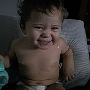Dalton is registered to the contest to win money with this photo: toddler, child, smiling, diaper, indoor, toy, pillow, bare_chest, happy, cute, baby, person, young_child, sitting, face, head, hair, skin, infant, room