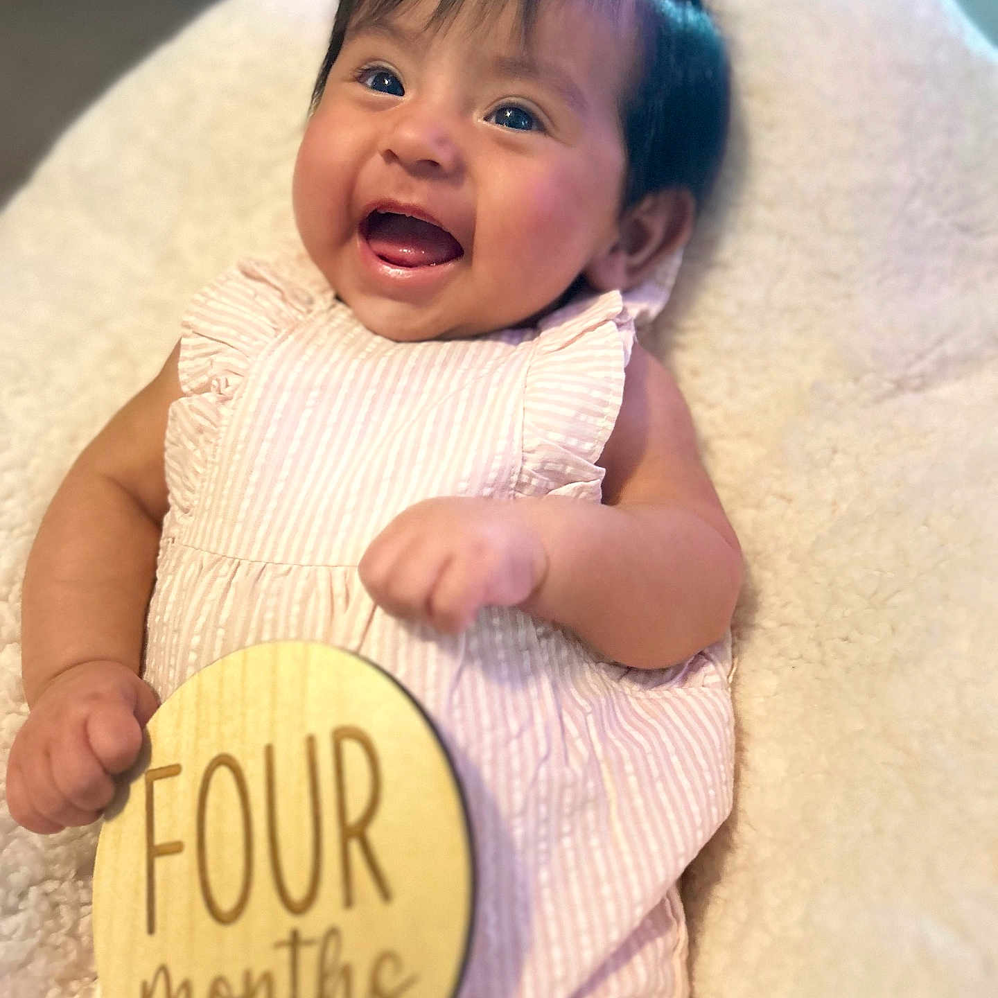 Camila is registered to the contest to win money with this photo: adorable, baby, cheerful, child, closeup, cute, face, four_months, hand, happy, indoors, infant, lying_down, pink_bow, portrait, smiling, soft_blanket, striped_dress, wooden_sign, young