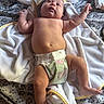 Bryce is registered to the contest to win money with this photo: baby, infant, diaper, towel, bedspread, pattern, arms, legs, skin, bare_chest, curious, lying_down, soft_texture, yellow_trim, floral_pattern, newborn, indoors, child, person, cute