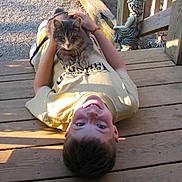 Spartacus joined the competition — help win amazing prizes! boy, cat, wooden_deck, sunlight, outdoor, statue, smiling, pet, relaxing, casual_clothing, daylight, child, animal, playful, nature, portrait, hands, resting, happy, leisure