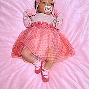 Rose is registered to the contest to win money with this photo: baby, infant, pink, dress, headband, pacifier, sock, blanket, lying_down, cute, child, soft_texture, gloves, footwear, portrait, newborn, sleepwear, indoors, fashion, adorable