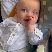 Nino participe au concours pour gagner de l'argent avec cette photo : baby, infant, thumb_sucking, white_shirt, blue_eyes, car_seat, safety_strap, pillow, blanket, polka_dots, patterned_fabric, cute, smile, portrait, indoor, soft_light, hand, face, young_child, happy