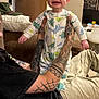 Matthew joined the competition — help win amazing prizes! baby, child, dinosaur_pajamas, tattoos, smile, happy, indoor, living_room, person, couch, pillow, door, ceiling_light, adult_hands, clothing, home, furniture, joyful, infant, casual