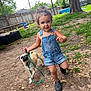 Cash joined the competition — help win amazing prizes! child, toddler, dog, leash, denim_overalls, backyard, grass, tree, fence, footwear, playful, outdoor, pet, canine, person, summer, nature, happy, walking, young_child