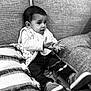 Shayel participe au concours pour gagner de l'argent avec cette photo : toddler, child, baby, couch, blanket, toy, indoor, clothing, jeans, shoes, hands, expression, face, sitting, playing, curious, monochrome, black_and_white, cozy, home