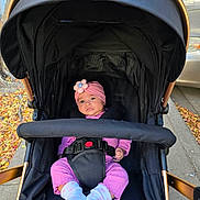 Gia is registered to the contest to win money with this photo: autumn_leaves, baby, baby_face, baby_girl, baby_socks, black_stroller, child, cute, daylight, flower, headband, infant, outdoor, pink_clothing, portrait, seat_belt, sidewalk, small_hands, stroller, urban