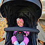 autumn_leaves, baby, baby_face, baby_girl, baby_socks, black_stroller, child, cute, daylight, flower, headband, infant, outdoor, pink_clothing, portrait, seat_belt, sidewalk, small_hands, stroller, urban