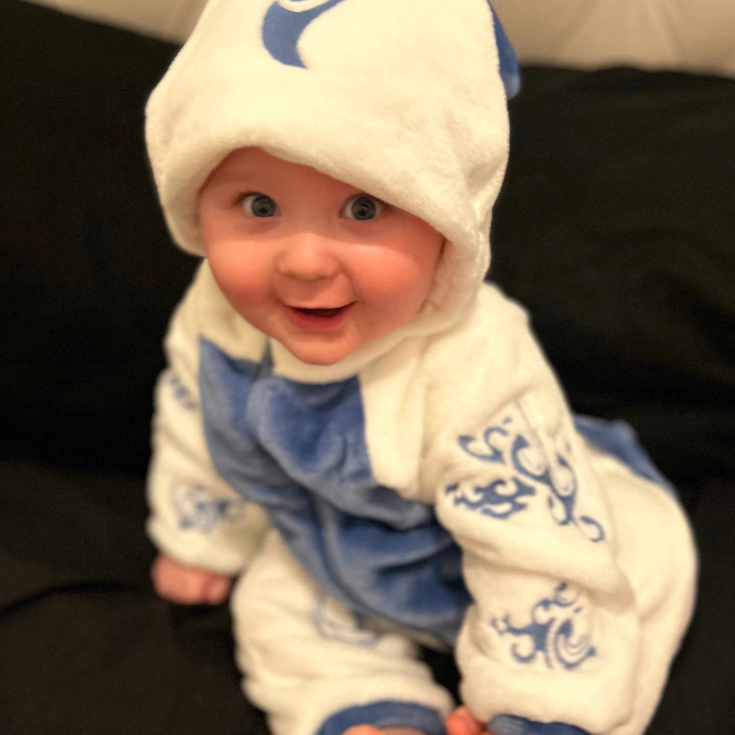 Luca is registered to the contest to win money with this photo: baby, bodypart, bonnet, cap, clothing, face, finger, hand, happy, hat, head, hood, hoodie, newborn, pants, person, photography, portrait, sitting, smile
