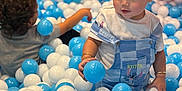 Henry is registered to the contest to win money with this photo: child, toddler, ball_pit, blue_balls, white_balls, playing, curly_hair, short_hair, overalls, stitch_character, indoor, fun, happy, cute, kids, toys, plastic_balls, play_area, colorful, smiling