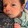 Khalil is registered to the contest to win money with this photo: baby, newborn, infant, close_up, face, hand, clothing, person, skin, expression, curious, eyes, hair, soft, fabric, grip, shirt, indoor, portrait, child