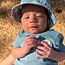 baby, infant, child, blue_clothing, bucket_hat, outdoor, sunlight, hands, face, expression, summer, nature, pine_needles, casual, cute, small_hands, person, young, portrait, daylight