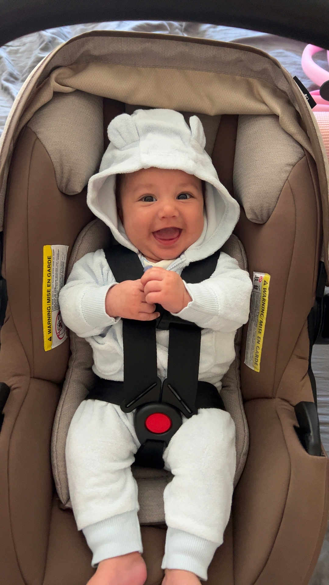 Khalil is registered to the contest to win money with this photo: baby, smiling, car_seat, white_clothing, hood, infant, cute, happy, child, safety_belt, indoor, seat, person, clothing, baby_clothes, newborn, joyful, cute_outfit, infant_care, child_safety
