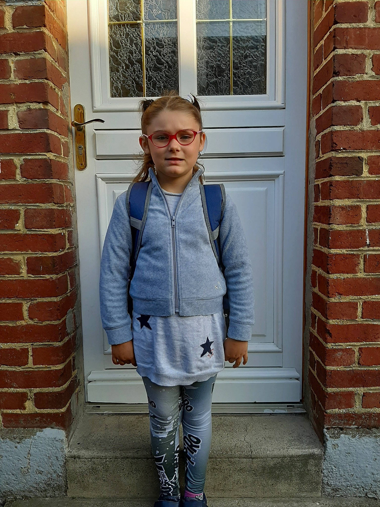 Enola participe au concours pour gagner de l'argent avec cette photo : brick, brickwork, child, child_model, clothing, denim, door, footwear, house, jacket, jeans, outerwear, person, shoe, snapshot, standing, street_fashion, t_shirt, top, window
